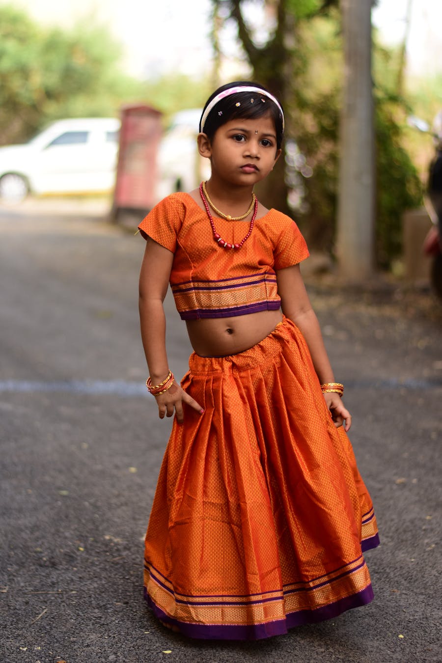 Young girl outdoors in an orange crop top and skirt with mirror tassels