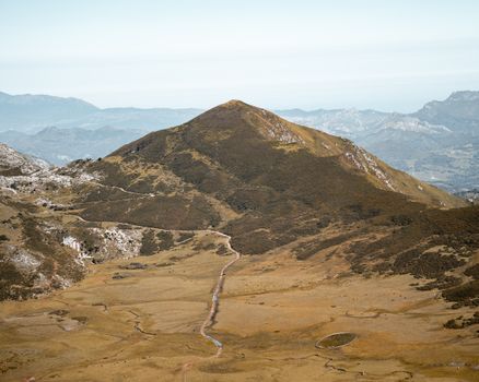 Aerial view of a vast brown mountain landscape under a clear sky.