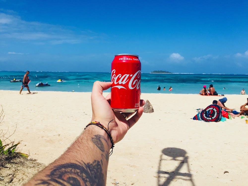 Person Holding Coca-cola Tin Can Near Shore