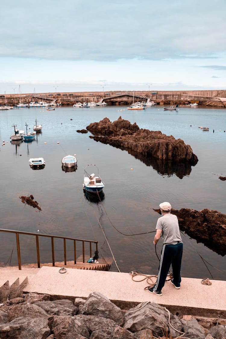 Man Pulling A Rope Attached To A Boat While Standing On A Pier