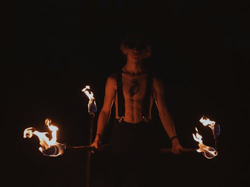 Man Holding Burning Torches in the Dark