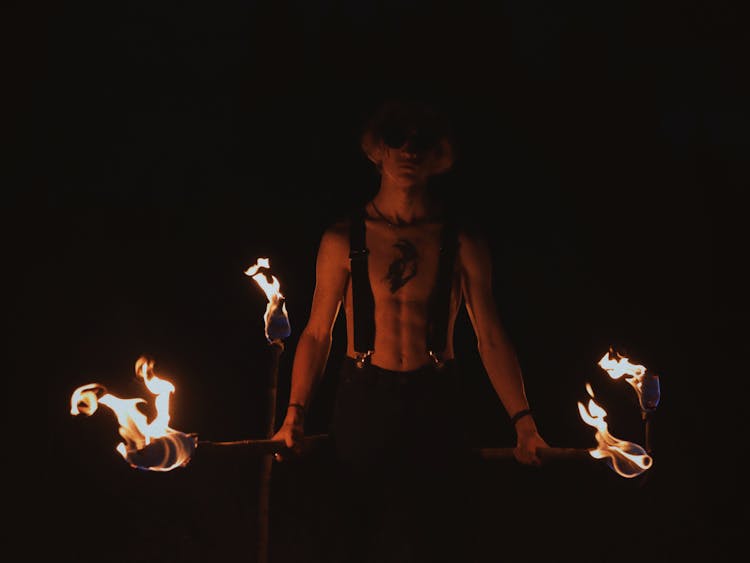 Man Holding Burning Torches In The Dark