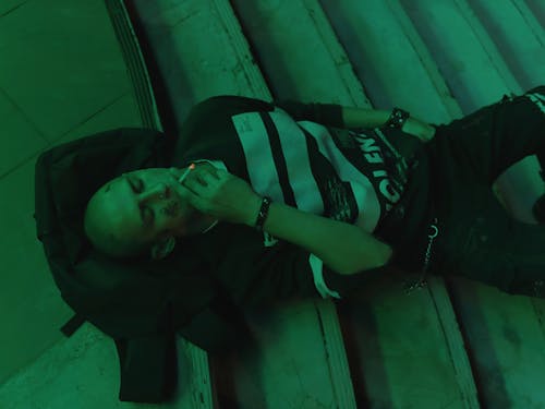 A Man Lying Down on the Stairs while Smoking 