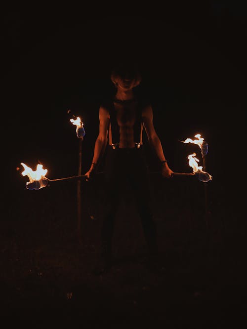 A Shirtless Man Holding a Lighted Torch