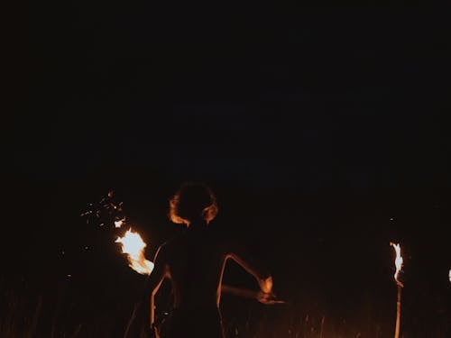 Back View Shot of a Man Dancing while Holding a Torch