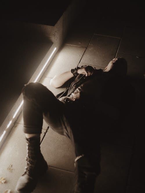 Photo of a Man Lying on the Ground Near a Light