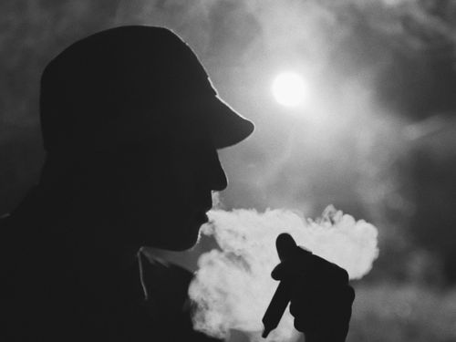 Free A dramatic black and white silhouette of a person smoking, with smoke swirling around. Stock Photo