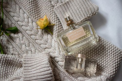 Free Luxurious Givenchy perfume bottles with a yellow rose on a knitted sweater, exuding elegance. Stock Photo