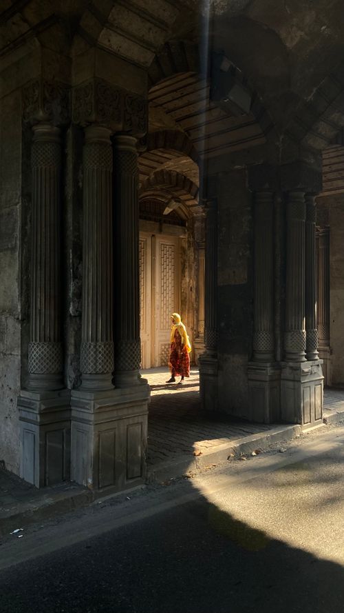 Free A person walking through a dramatic archway illuminated by sunlight. Stock Photo