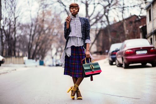 Woman Holding Handbag Beside Red Car on Road