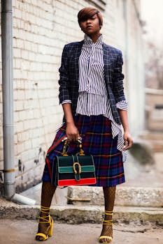 Stylish woman in striped blouse and plaid skirt posing outdoors in urban setting.