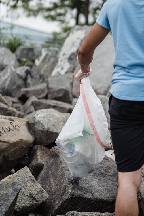 Woman in Blue Shirt and Black Shorts Holding White Plastic Bag