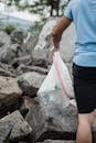 Woman in Blue Shirt and Black Shorts Holding White Plastic Bag