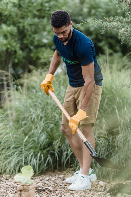 Man in Blue Shirt and Brown Pants Holding Brown Wooden Shovel
