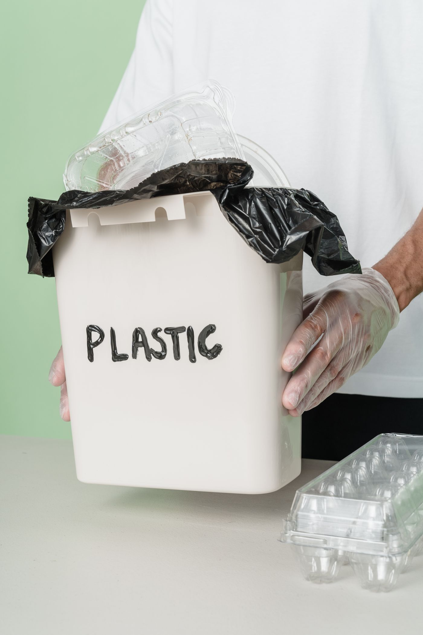 Person placing recyclable material into a blue recycling bin
