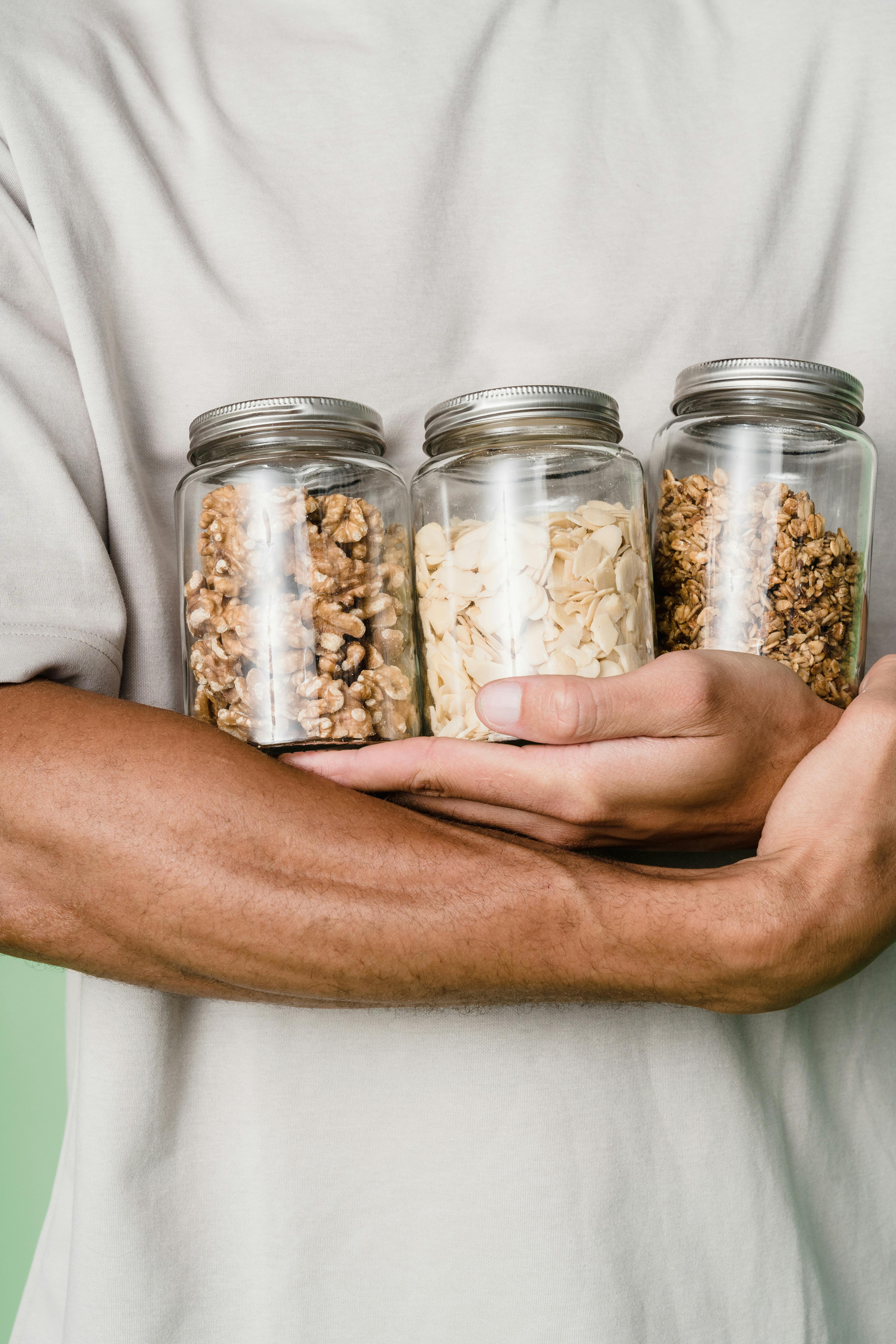 Premium Photo  Useful sweetness, nuts in honey in a glass jar, a man holds  in his hand