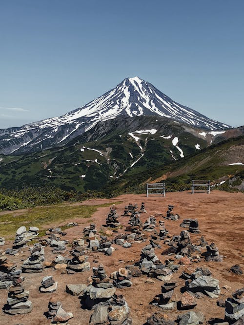 A Rocks on Brown Sand Near the Snow Covered Mountain Under the Blue Sky