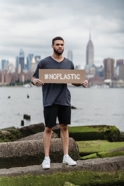 Man in Black Crew Neck T-shirt Holding the Beach Signage