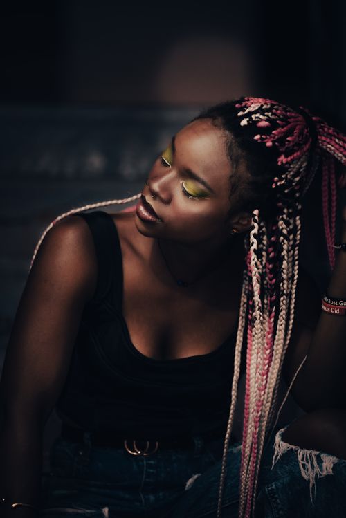 Free Portrait of an African American woman with vibrant braids and eye makeup, exuding confidence. Stock Photo
