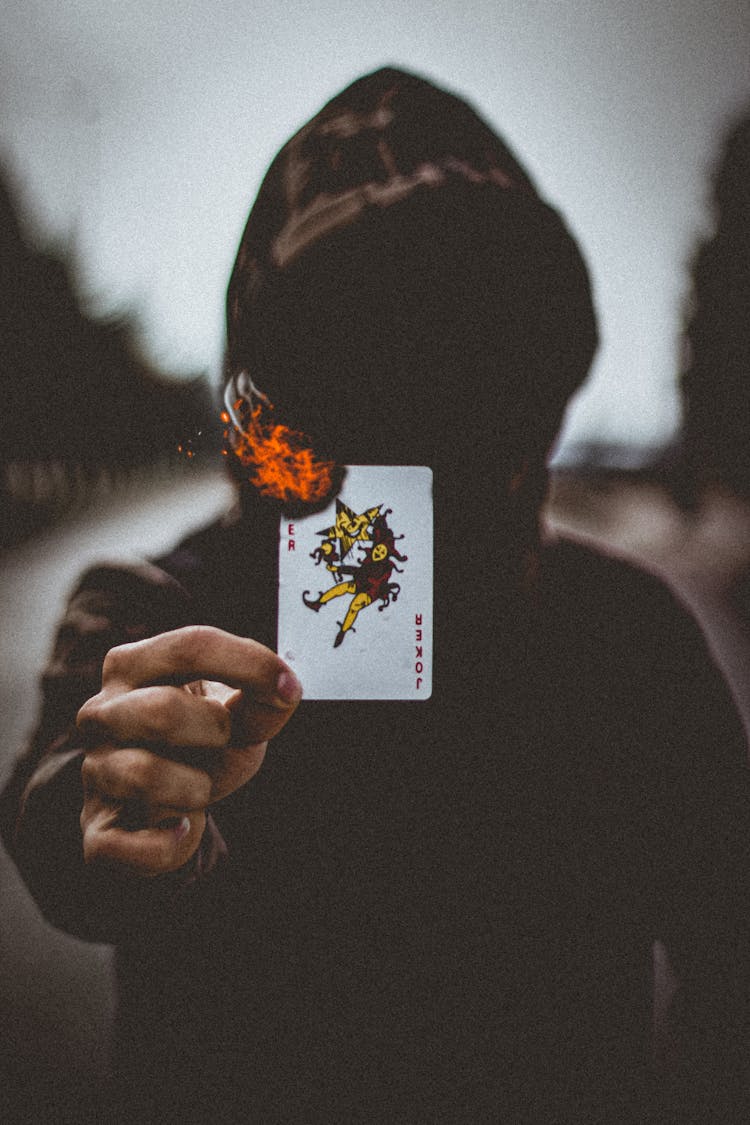 A Person Wearing Hoodie Holding A Burning Card