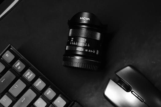 Top view of a camera lens, keyboard, and mouse on a minimalist workspace.