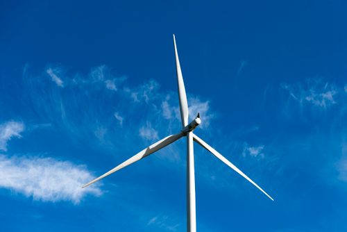 Free A powerful wind turbine stands tall under a clear blue sky, generating clean energy. Stock Photo