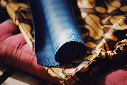 A close-up of a rolled blue yoga mat on colorful patterned fabric, highlighting fitness and relaxation.