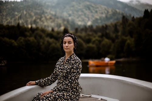 A Woman in Black Floral Dress Sitting on the Boat