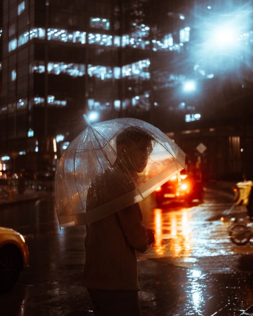 Free A person with an umbrella stands on a rainy Moscow street, illuminated by city lights. Stock Photo