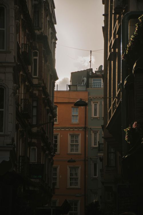 Free Dramatic narrow street scene with sunlit classic architecture and clouds. Stock Photo
