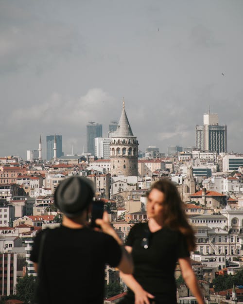 Man Taking a Photo of Woman and City