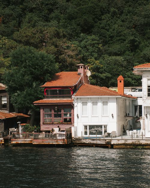 Free Scenic view of charming waterfront houses nestled by a lush forest, capturing tranquil summer vibes. Stock Photo