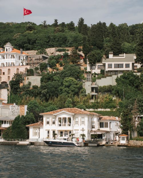 Free Scenic view of Istanbul's waterfront homes and lush greenery under a Turkish flag. Stock Photo