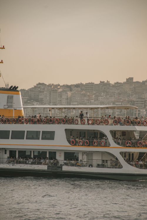Free Busy ferry with tourists sailing on urban waters against city backdrop. Stock Photo
