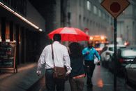 Man in White Dress Shirt and Blue Denim Jeans Holding Red Umbrella