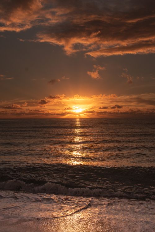 Free Stunning sunset over Curuípe Beach in Brazil highlighting a dramatic sky and reflective ocean waves. Stock Photo