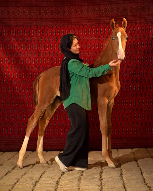 Woman in Black Long Sleeve Shirt Standing Beside Brown Horse