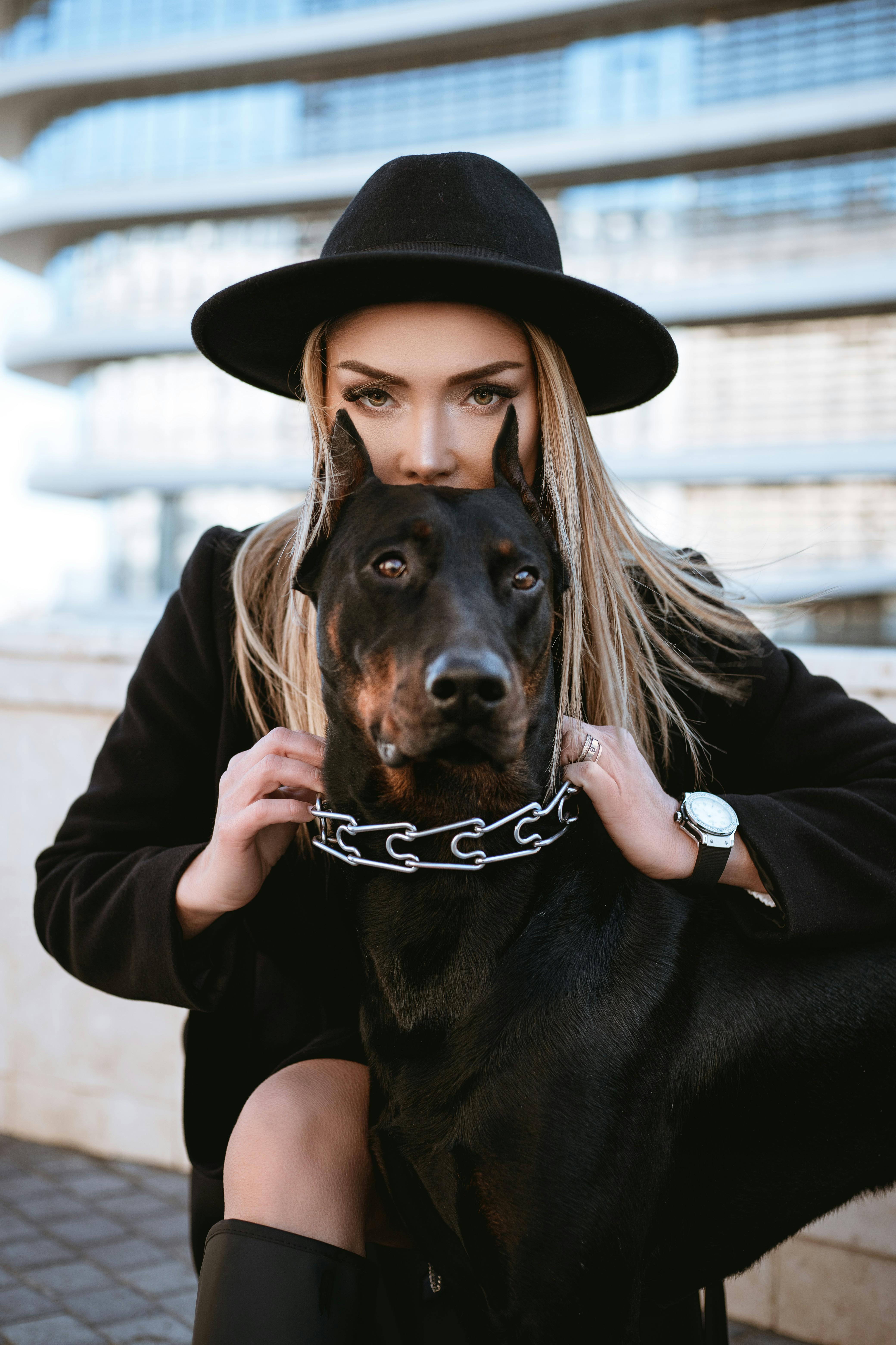 woman in black jacket holding black and brown short coated dog