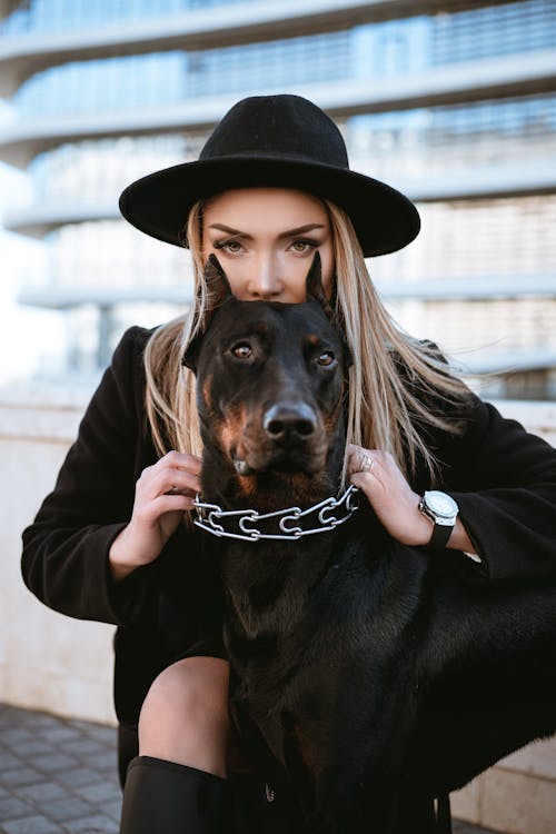 Woman in Black Jacket Holding Black and Brown Short Coated Dog