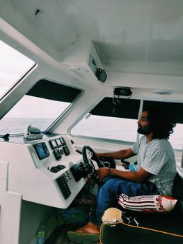 Man steering a motorboat in the Maldives, capturing oceanic adventure and travel spirit.