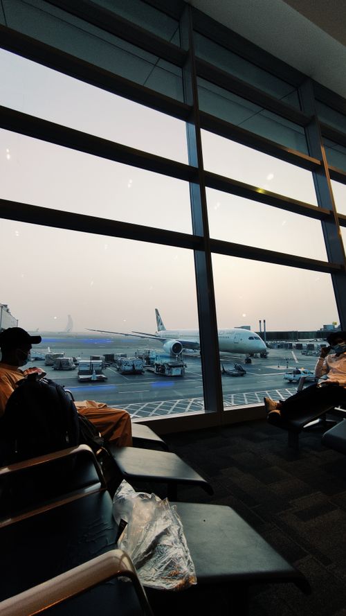 Free Airplane on tarmac viewed through windows in Abu Dhabi's airport lounge at sunset. Stock Photo