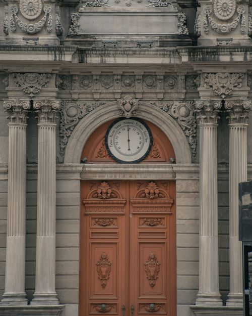 Free A detailed facade of a historic building featuring ornate architecture and a central clock. Stock Photo