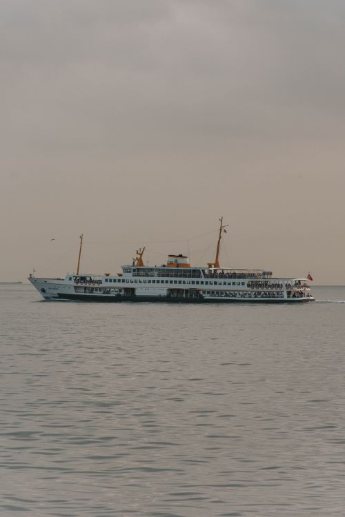 Free Passenger ferry sailing across a calm ocean under a cloudy sky, showcasing maritime travel Stock Photo
