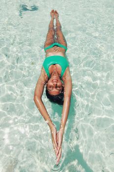 Woman enjoying a peaceful float in the clear waters of Dhangethi, Maldives.