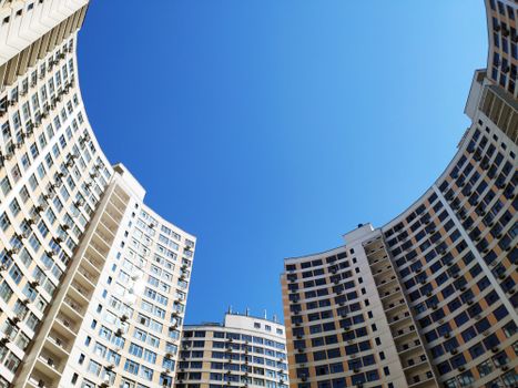 Low angle view of modern high-rise residential buildings under a clear blue sky, emphasizing architectural design.