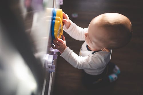 Free High-Angle Shot of a Kid Playing with a Blue and Yellow Toy Stock Photo