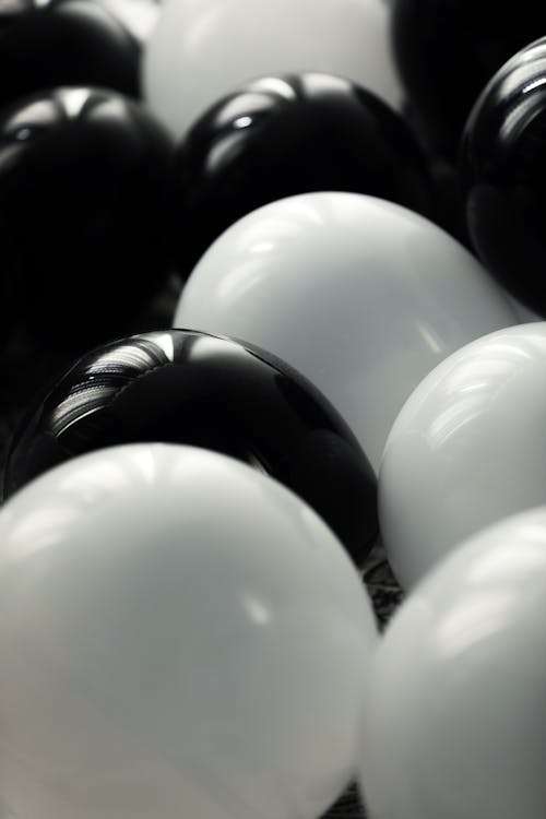 Black and white bunch of big different colored balloons inflated with helium placed in light room during festive event celebration