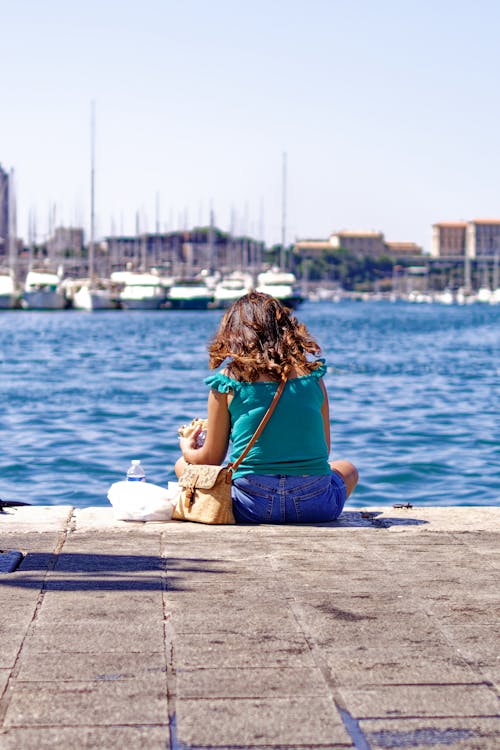 Woman in Blue Tank Top Sitting on Concrete Dock