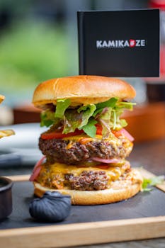 Delicious double cheeseburger with lettuce, tomato, and pickles stacked between buns, served with fries.