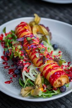 Delicious gourmet dish with berries, greens, and raspberry sauce drizzle on a white plate.